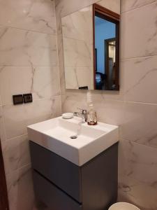 La salle de bains est pourvue d'un lavabo blanc et d'un miroir. dans l'établissement Bel appartement au centre de Casa, à Casablanca