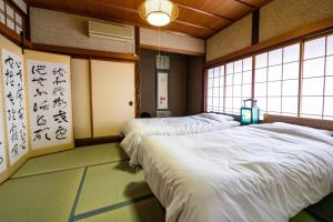 two beds in a room with a room with writing on the wall at ゲストハウス　luluha in Awatabe