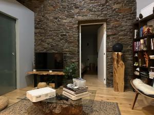 sala de estar con pared de piedra y TV en Quinta dos Piscos, en Barcos