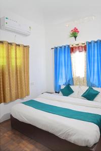 a bedroom with a large bed with blue curtains at Noble Homestay in Munnar