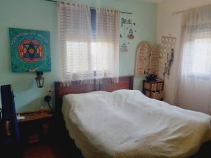 בוסתן בנגב في Netivot: غرفة نوم بسرير وملاءات بيضاء ونوافذ