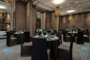 une salle de conférence avec des tables, des chaises et des lustres dans l'établissement Hyatt Centric Candolim Goa, à Calangute