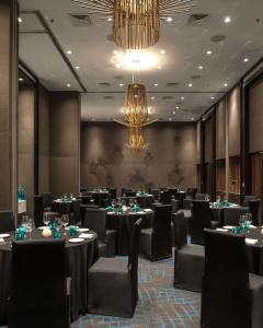 une salle de banquet avec des tables et des chaises ainsi qu'un lustre dans l'établissement Hyatt Centric Candolim Goa, à Calangute