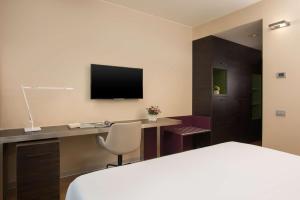 a hotel room with a bed and a desk with a television at NH Orio Al Serio in Orio al Serio