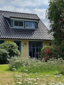 żółty dom z szarym dachem i dziedzińcem w obiekcie Kinderfreundliche Ferienanlage in idyllischer Lage w mieście Neuenkirchen