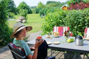 kobieta w kapeluszu siedząca przy stole w obiekcie Kinderfreundliche Ferienanlage in idyllischer Lage w mieście Neuenkirchen