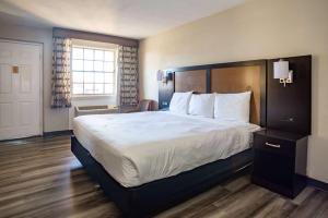 una habitación de hotel con una cama grande con sábanas blancas en Baymont by Wyndham Austin University Area, en Austin