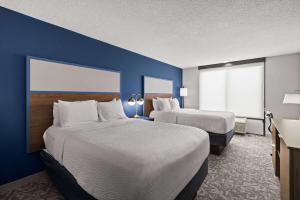 卡斯帕爾的住宿－AmericInn by Wyndham Casper Event Center Area，酒店客房设有两张床和蓝色的墙壁。