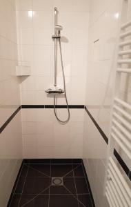 een douche met een slang in een wit betegelde badkamer bij Houterhoeve in Swalmen