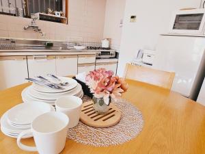 a table with plates and cups and a vase with flowers at AsahiStay -Koiwa, Free parking O, Whole Family House, Japanese garden taste in Tokyo +44 photos