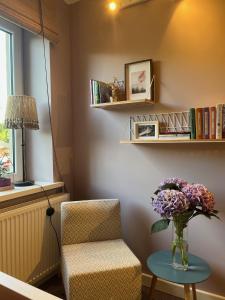 um quarto com uma cadeira e um vaso de flores sobre uma mesa em Art&Comfort Country em Kaunas