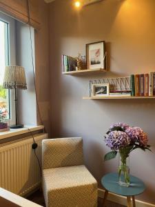 a room with a chair and a vase of flowers on a table at Art&Comfort Country in Kaunas