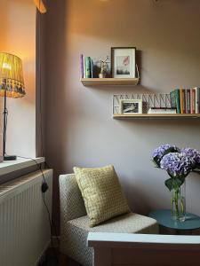 uma sala de estar com uma cadeira e um vaso de flores sobre uma mesa em Art&Comfort Country em Kaunas