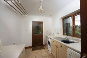 a kitchen with a sink and a washing machine at Godolphin in Wadebridge