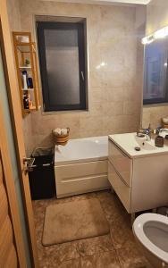 ein Badezimmer mit einer Badewanne, einem Waschbecken und einem WC in der Unterkunft Iaki Apartment Mamaia in Mamaia