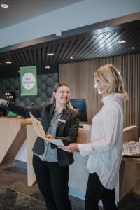 Dos mujeres están frente a un mostrador. en Holiday Inn Lübeck, an IHG Hotel, en Lübeck