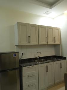 a kitchen with white cabinets and a sink and a refrigerator at Star Dubai Apartment in Salalah