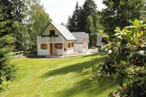 een klein huis in een tuin met een groen gazon bij Gemütliche BERGHüTTE-1 am Bach mit Zugang zur Sauna, heißen Badewanne und Pool in Szklarska Poręba