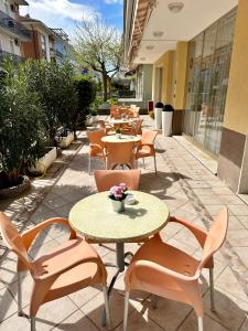 a patio with tables and chairs and a table with flowers at Hotel Enna Rimini in Rimini