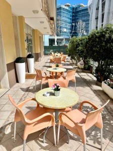 eine Reihe von Tischen und Stühlen auf einer Terrasse in der Unterkunft Hotel Enna Rimini in Rimini