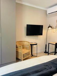 a bedroom with a television and a chair and a table at Executive Studio Apartment in Sandton in Johannesburg