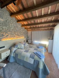 a bedroom with a bed and a stone wall at Casa Rural Can Titus in L’ Esquirol