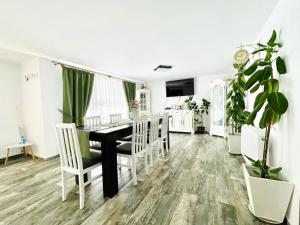 a dining room with a black table and white chairs at Agropa Rooms & Garden Events in Bistriţa