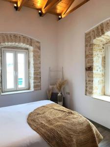 1 dormitorio con 1 cama blanca y 2 ventanas en Mangata suites homes with private pools, en Meganisi