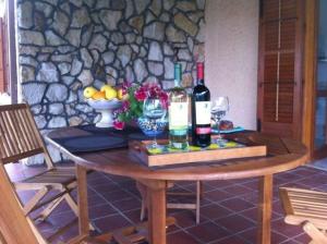 una mesa con 2 botellas de vino y un bol de fruta en Ferienhaus für 5 Personen ca 80 qm in Scopello, Sizilien Nordküste von Sizilien, en Scopello