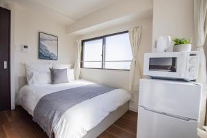 a bedroom with a bed with a microwave and a window at Walk to Nishi-Nippori/Sendagi/Nippori sta. DBoY in Tokyo