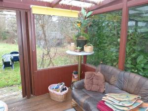 a couch on a screened in porch with a table at Freistehendes Ferienhaus in Adendorf mit Terrasse, Grill und Garten in Adendorf +14 photos