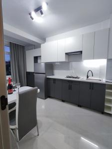 eine Küche mit weißen Schränken, einem Tisch und einem Waschbecken in der Unterkunft Chisinau Central Apartments in Chişinău