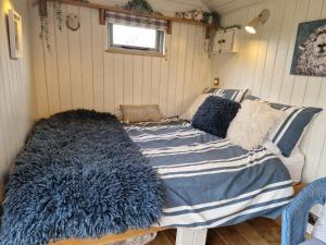a bed with a blue and white blanket and pillows at Dolly at Lowlands in Ringwood