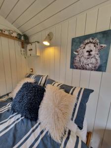 a bed with pillows and a picture of a sheep at Dolly at Lowlands in Ringwood