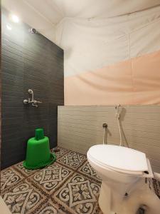 a bathroom with a toilet and a green bucket at Dandeli Jungle Stay in Dandeli