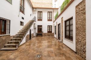 an internal courtyard of a house with stairs and windows at Apartamentos Jardines de la Sitarilla in Granada