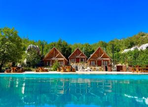 una fila de cabañas junto a una piscina de agua en Wood Hills Hotel & Resort, en Mayrūbā