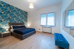1 dormitorio con cama con colcha azul y pared de flores en Art Gallery Rimini Apartments 130mq Esclusivo, en Rímini