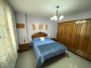 1 dormitorio con 1 cama azul y armarios de madera en Villa Caniles en Caniles