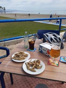 a table with two plates of food and a glass of beer at Apartamentos Roquetas Beach in Roquetas de Mar
