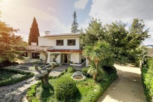 a house with trees and bushes in front of it at Grand Luxury Villa Piscina & Jacuzzi Granada in Albolote