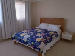 1 Schlafzimmer mit einem Bett mit einer Blumendecke und einem Fenster in der Unterkunft Mansion @ the Coast in Albion Park