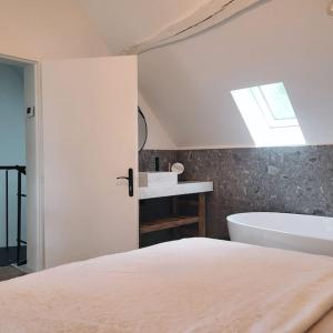 a bedroom with a white bed and a bath tub at Gîte au Haras d'Agathe et ses princes in Les Barils