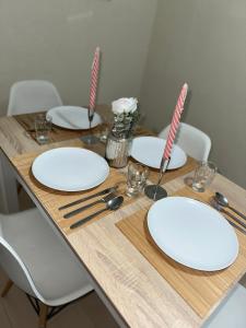 una mesa de madera con platos y utensilios blancos. en Love Fuencarral, en Madrid