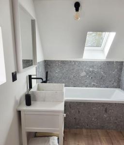 een badkamer met een wastafel en een bad bij Gîte au Haras d'Agathe et ses princes in Les Barils