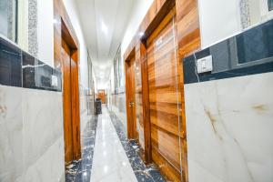 Un pasillo con puertas de madera y paredes de mármol. en FabHotel Vihaan Regency, en Nueva Delhi