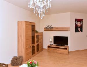 a living room with a television and a chandelier at Appartement in Saig mit Garten und Grill in Lenzkirch