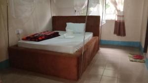 Cama en habitación con pared de cristal en BM. Beach hotel at Nansio, Ukerewe island, en Hamukoko