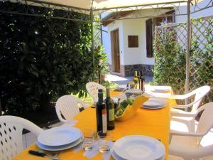 een houten tafel met witte stoelen en wijnflessen erop bij Ferienhaus auf dem Bio-Bauernhof Poggio alla Cavalla in Lazzeretto