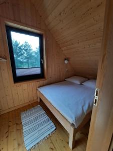 Łóżko w drewnianym pokoju z oknem w obiekcie Domki nad Kukówkiem w mieście Wdzydze Tucholskie